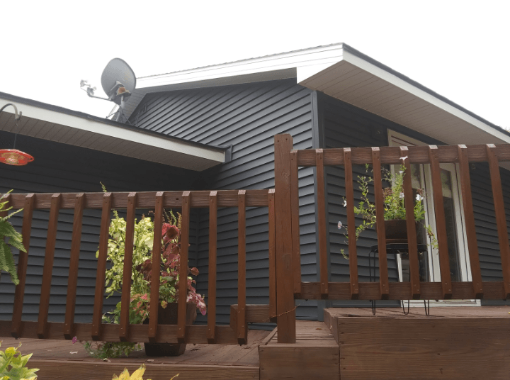 A house with a wooden fence and a satellite dish on the roof.