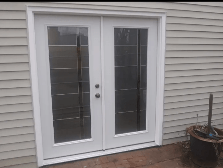 A pair of white sliding glass doors on the side of a house.