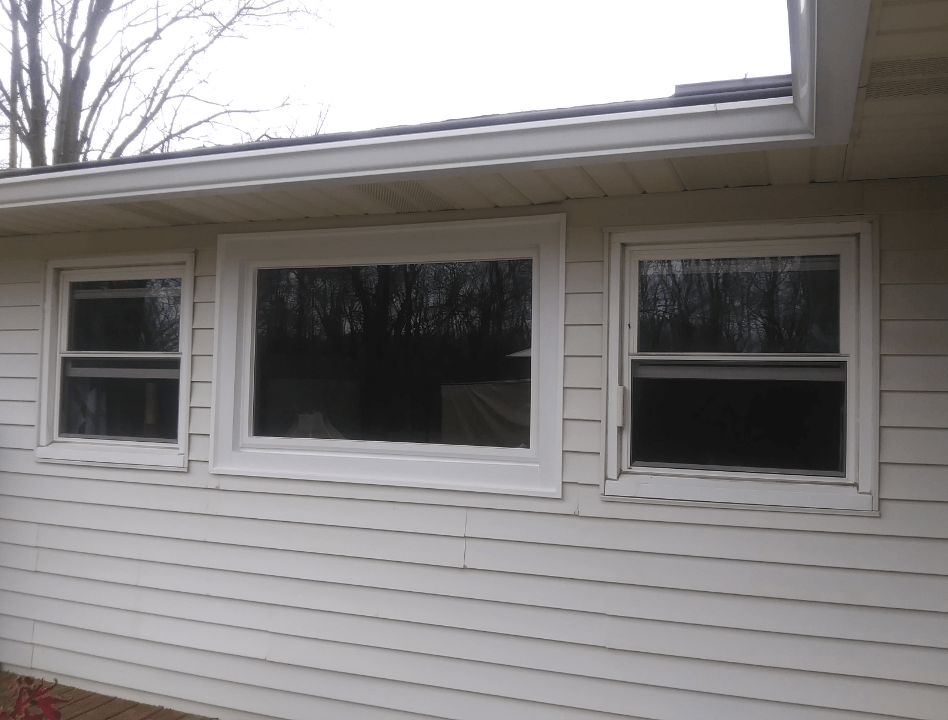A white house with three windows and a roof.