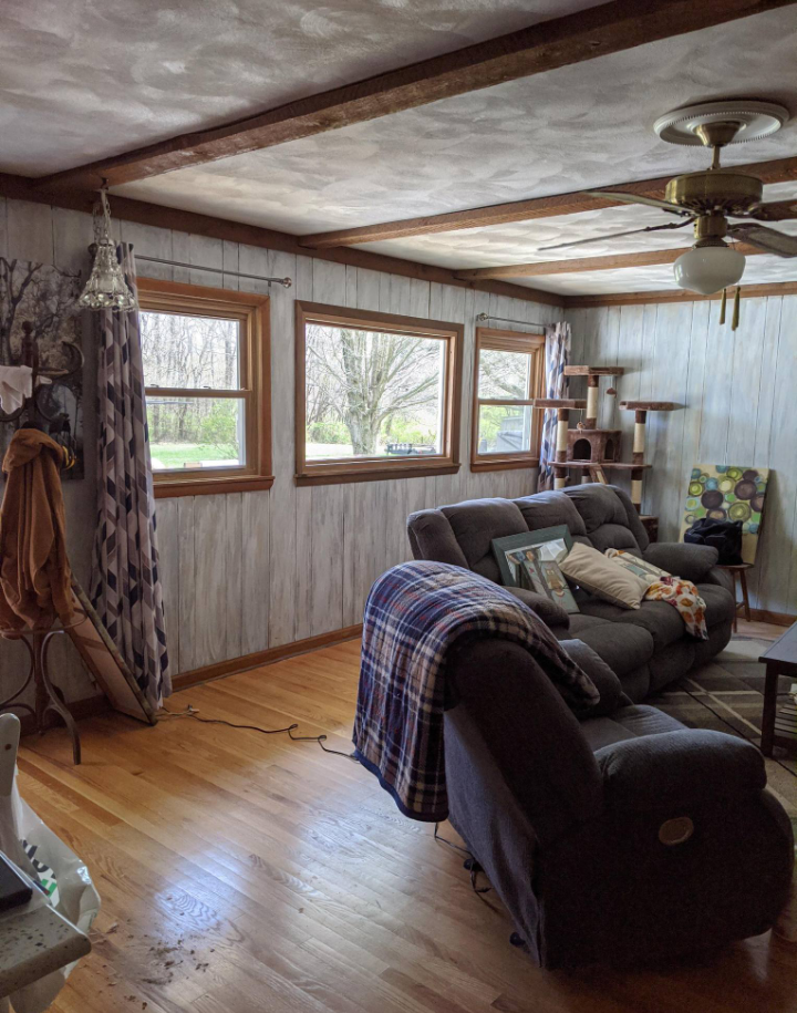 A living room with a couch , chair , table and ceiling fan.