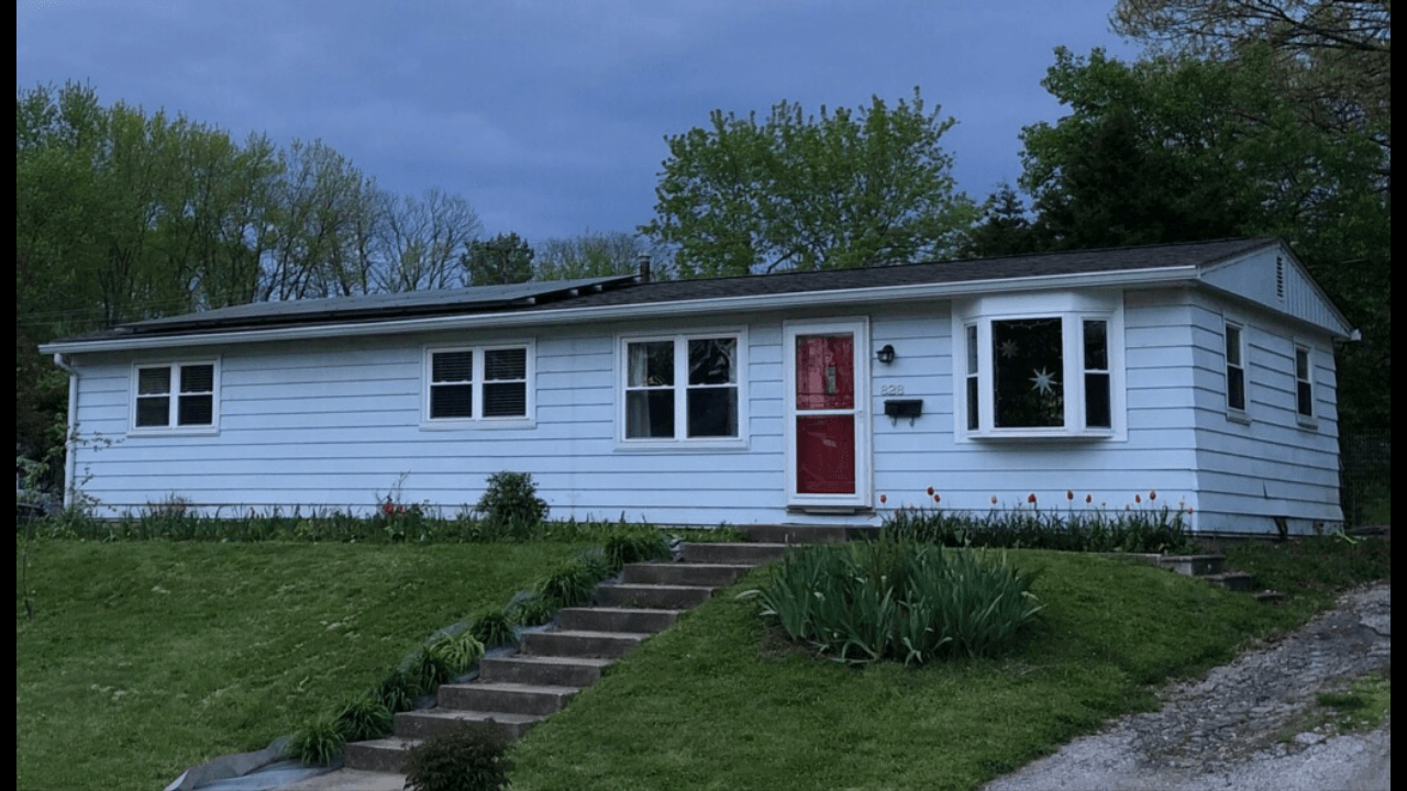 A white house with a red door and stairs leading up to it.