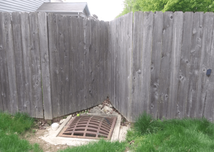 A wooden fence with a drain in the middle of it.