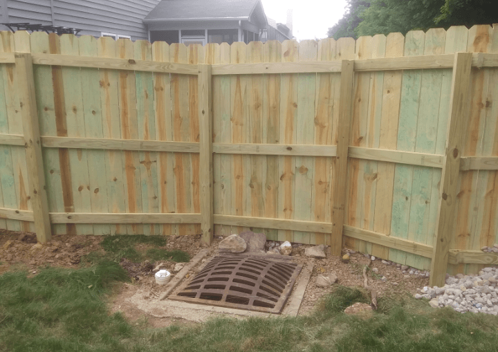 A wooden fence with a drain in the middle of it.