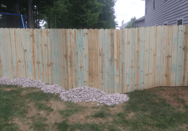 A wooden fence is in the backyard of a house.