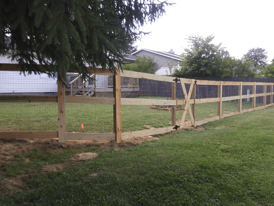 A wooden fence is sitting in the middle of a lush green field.