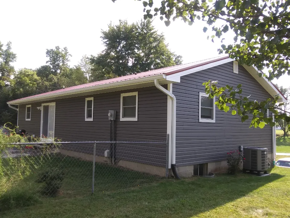 A gray house with a red roof and white trim