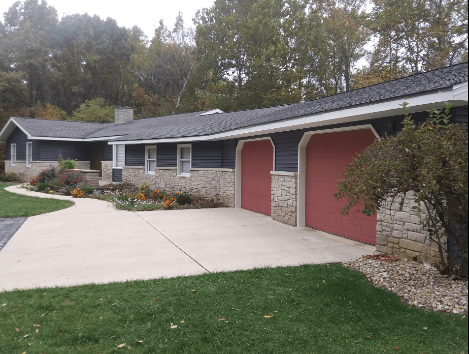 A house with two red garage doors and a concrete driveway