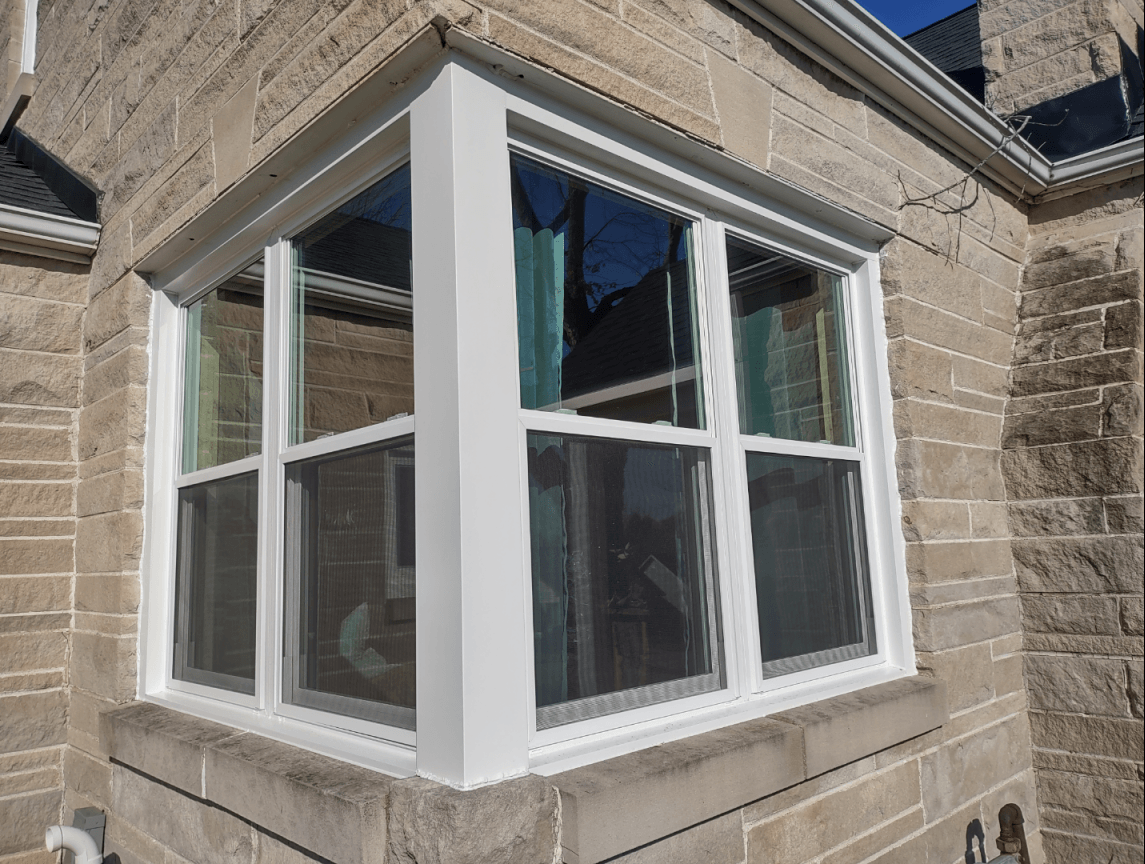 A white window on the side of a brick building.