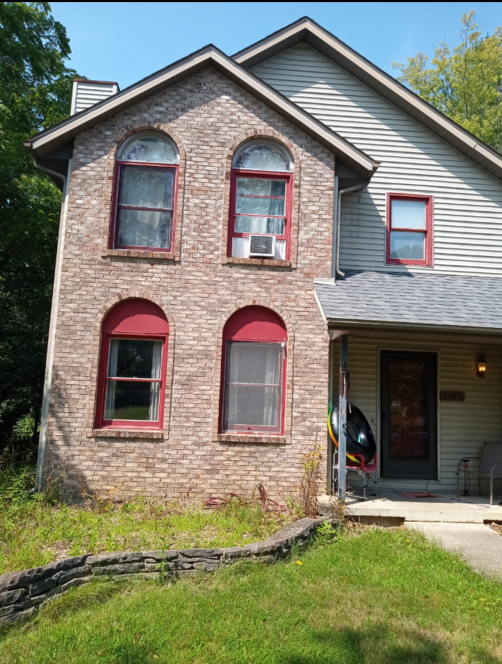 A brick house with arched windows and a gray roof