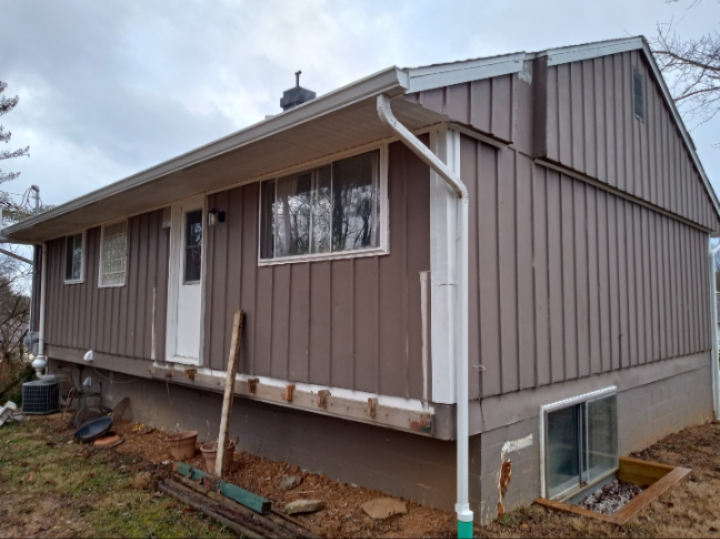 A brown house with a gutter on the side of it.