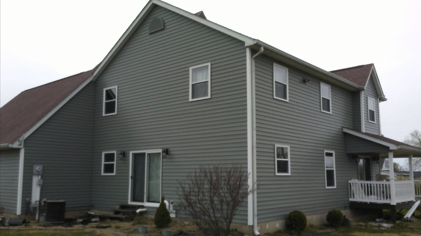 A large gray house with a red roof and many windows