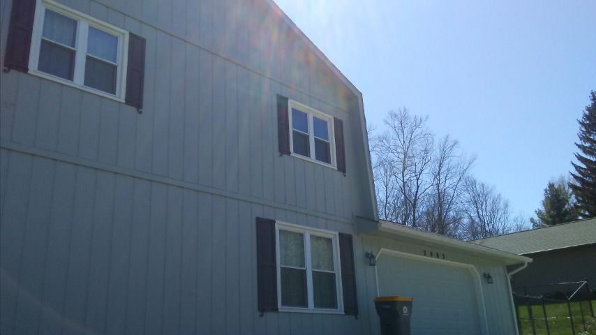 A gray house with black shutters and a garage on a sunny day.