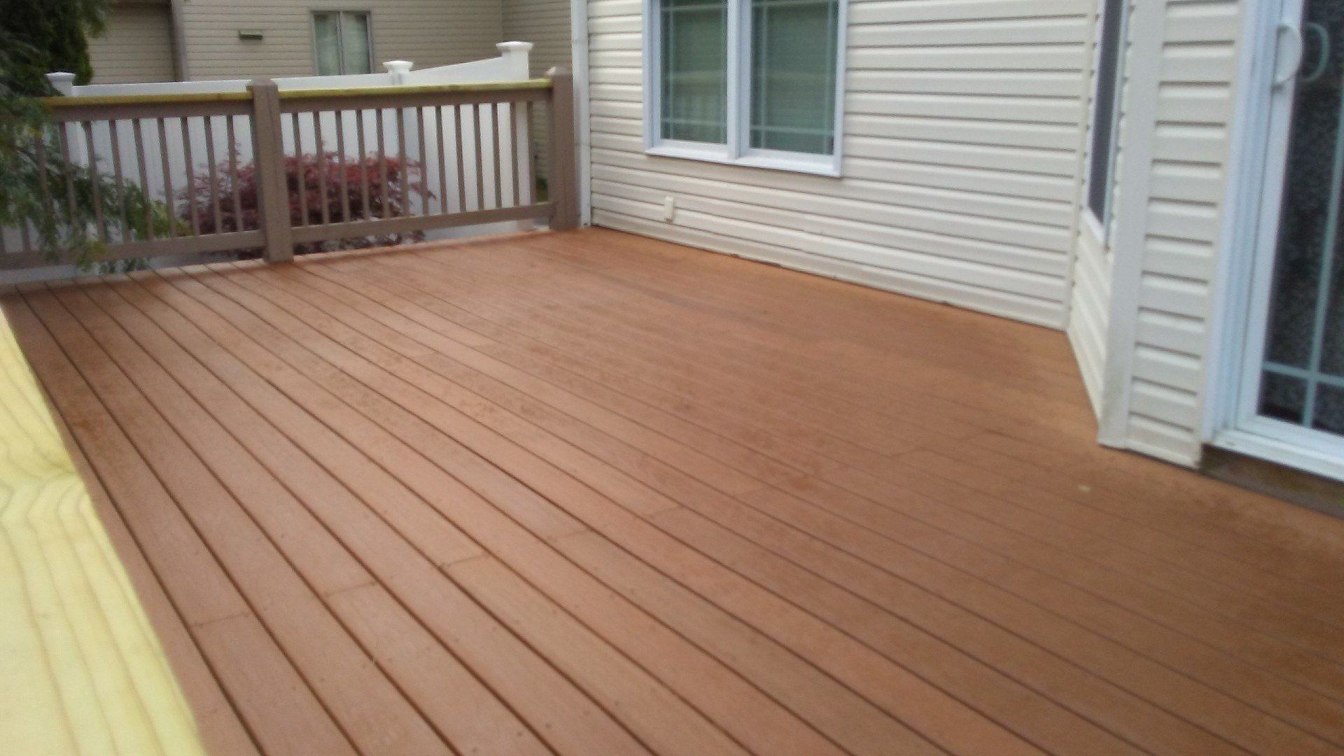 A wooden deck with a white house in the background.