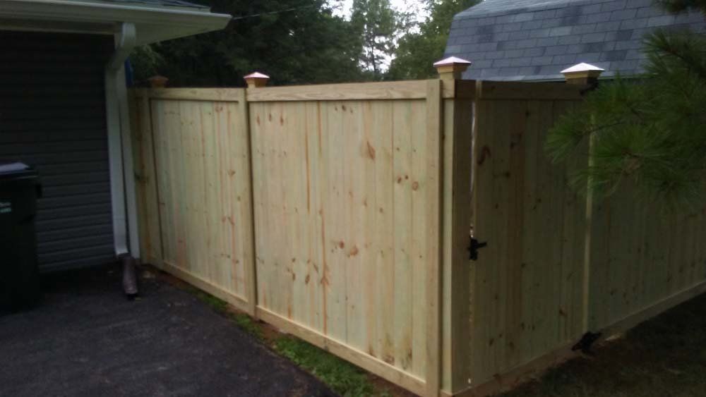 A wooden fence with a gate is sitting next to a house.