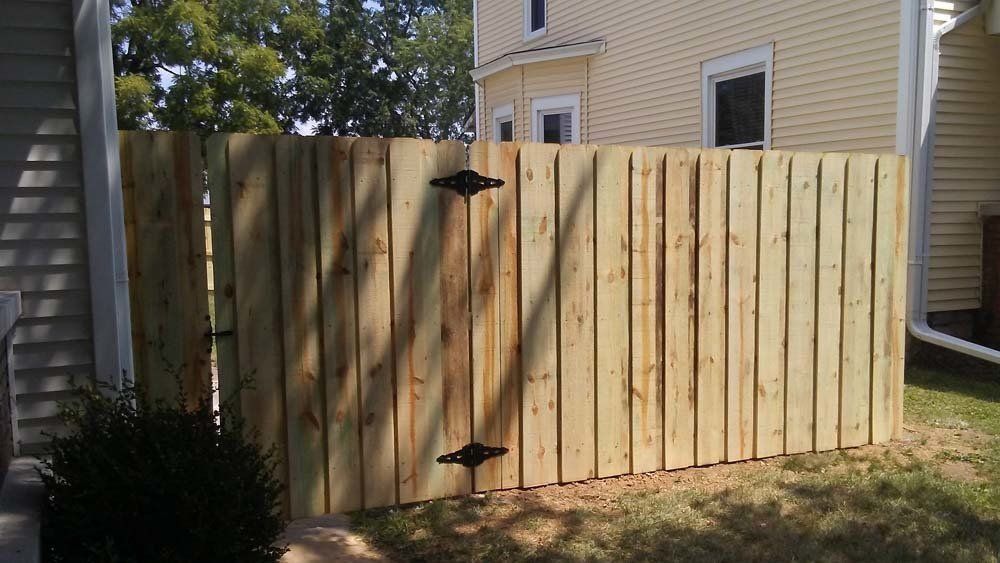 A wooden fence with a gate in front of a house.