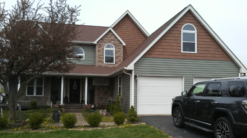 A black suv is parked in front of a large house.