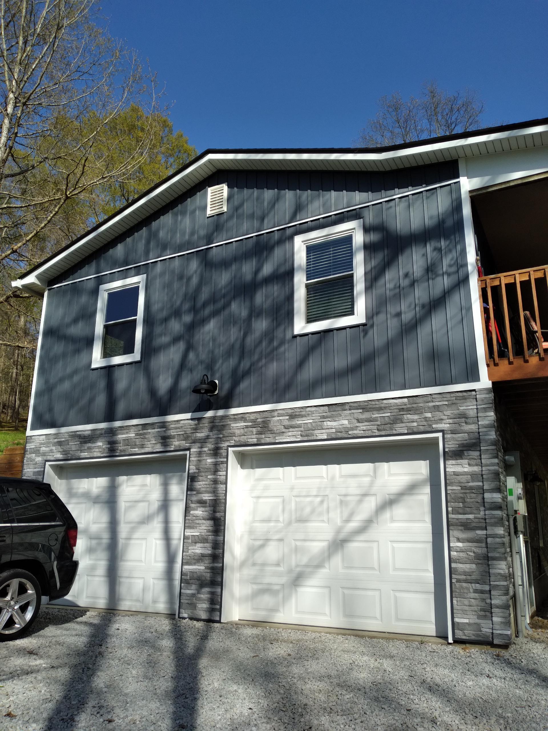 A house with two garage doors and a truck parked in front of it.