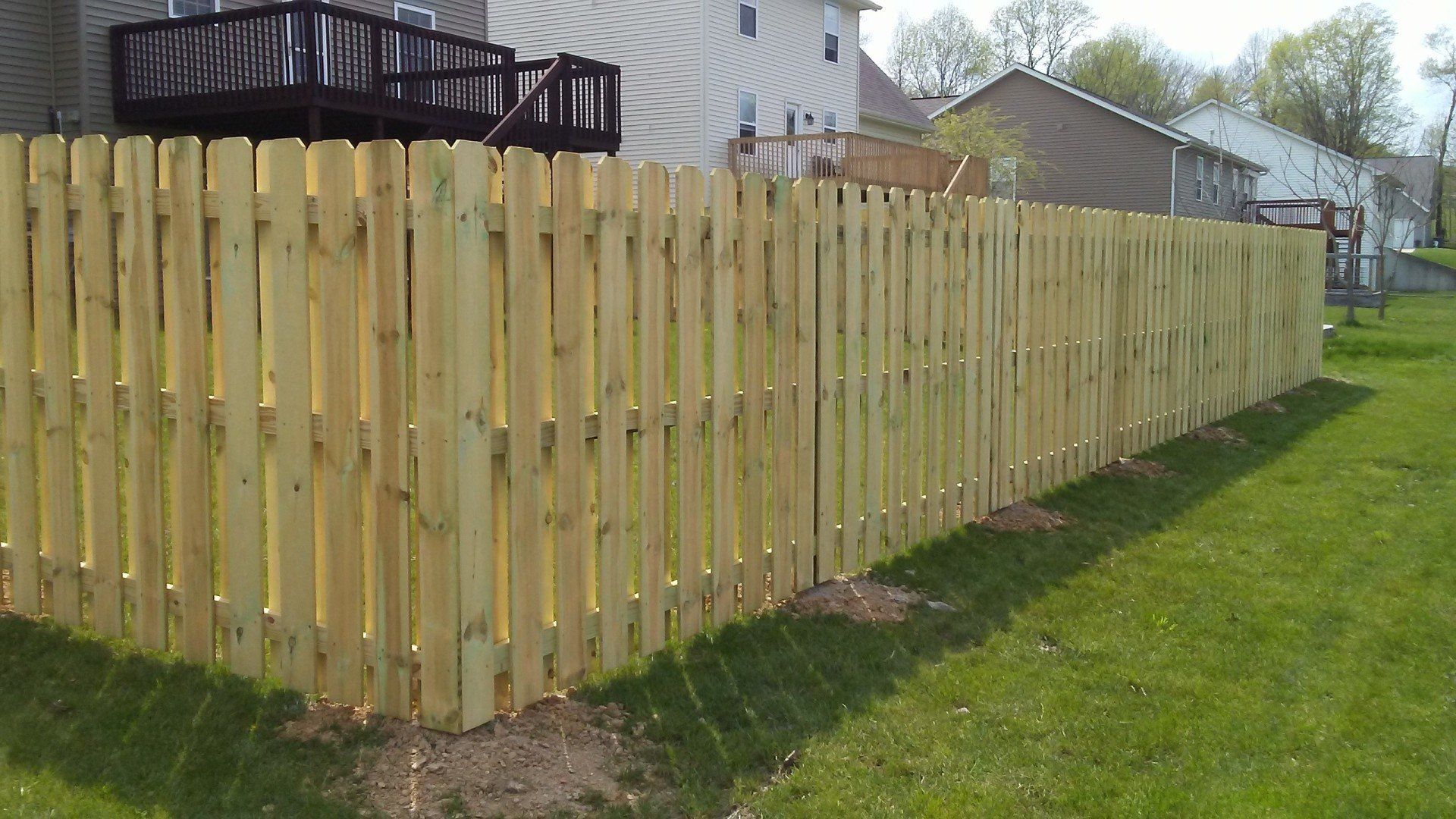 A wooden fence is sitting in the grass in front of a house.