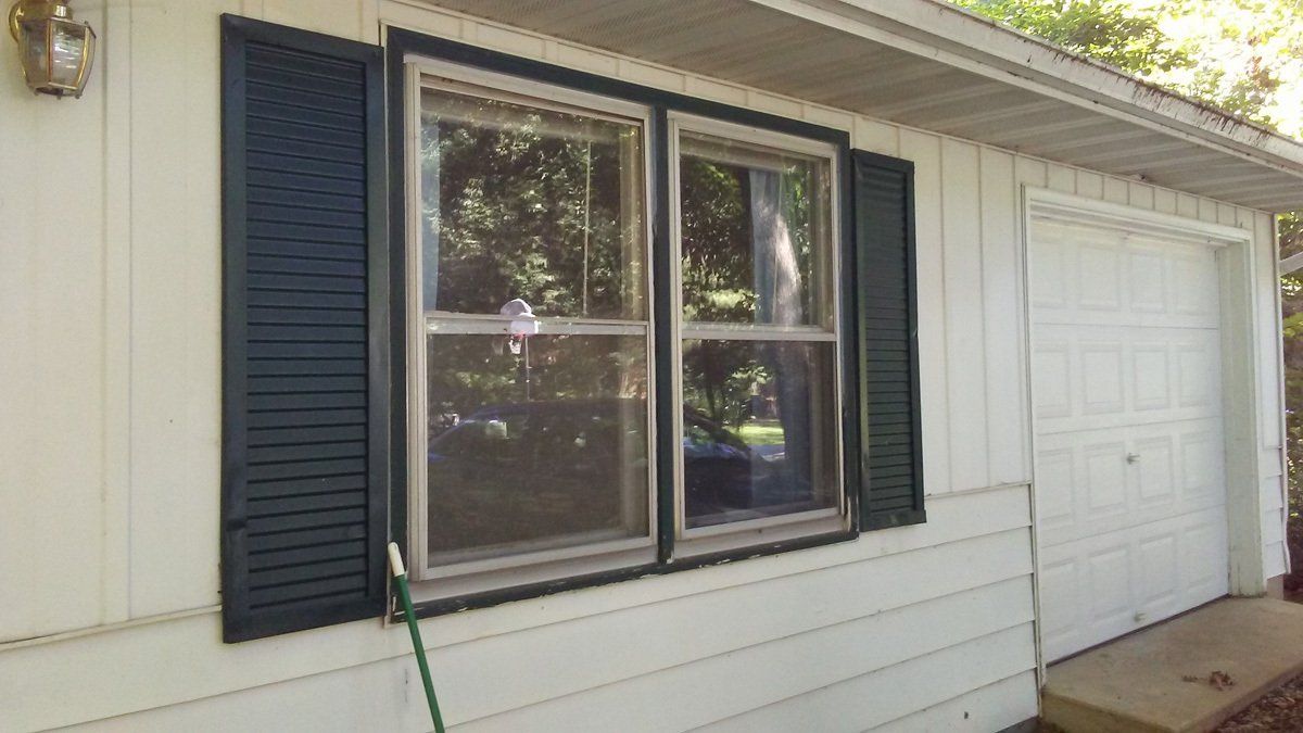 A white house with black shutters and a garage door.