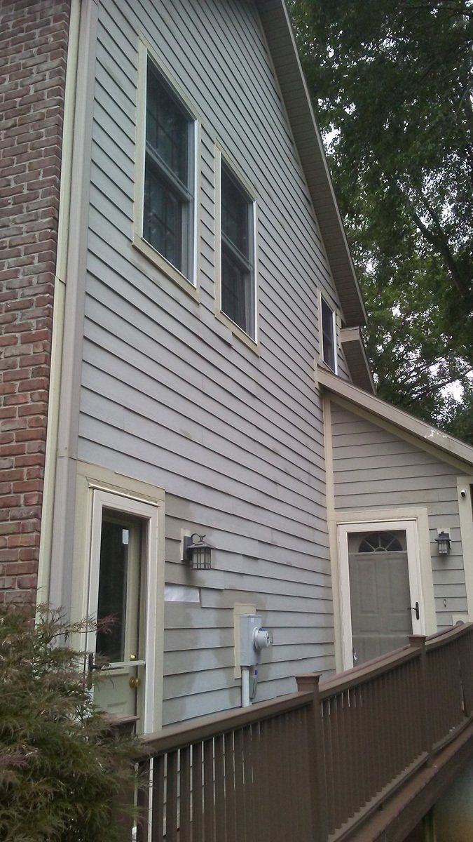A white house with a brick wall and a wooden deck.