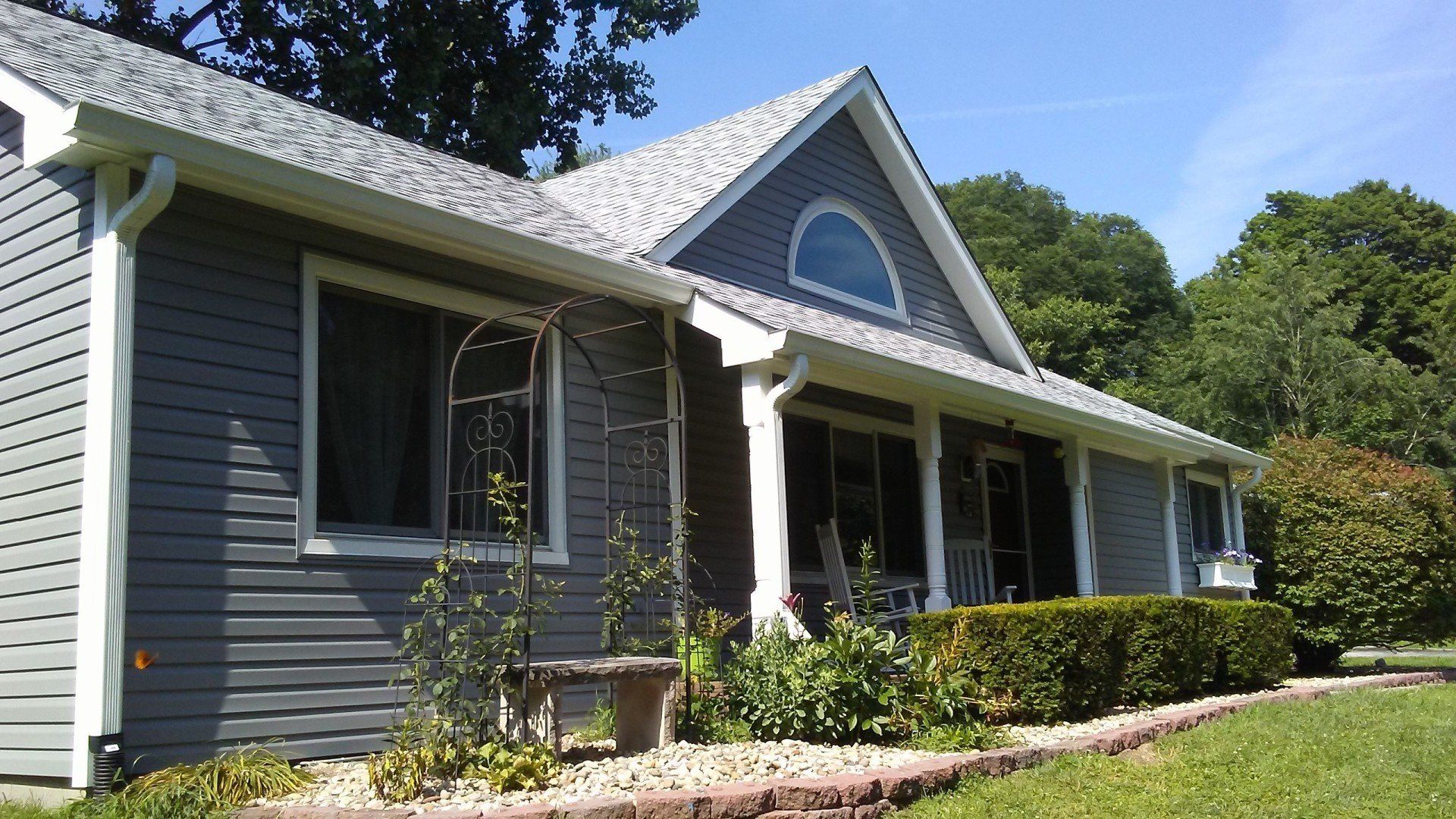 A gray house with a white trim and a porch