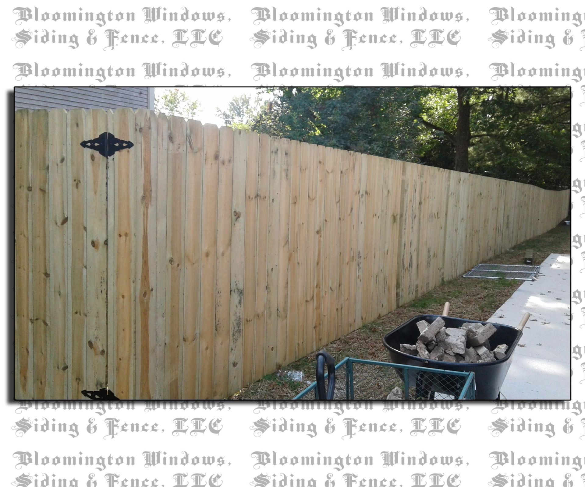 A wooden fence is being built by bloomington windows siding & fence llc