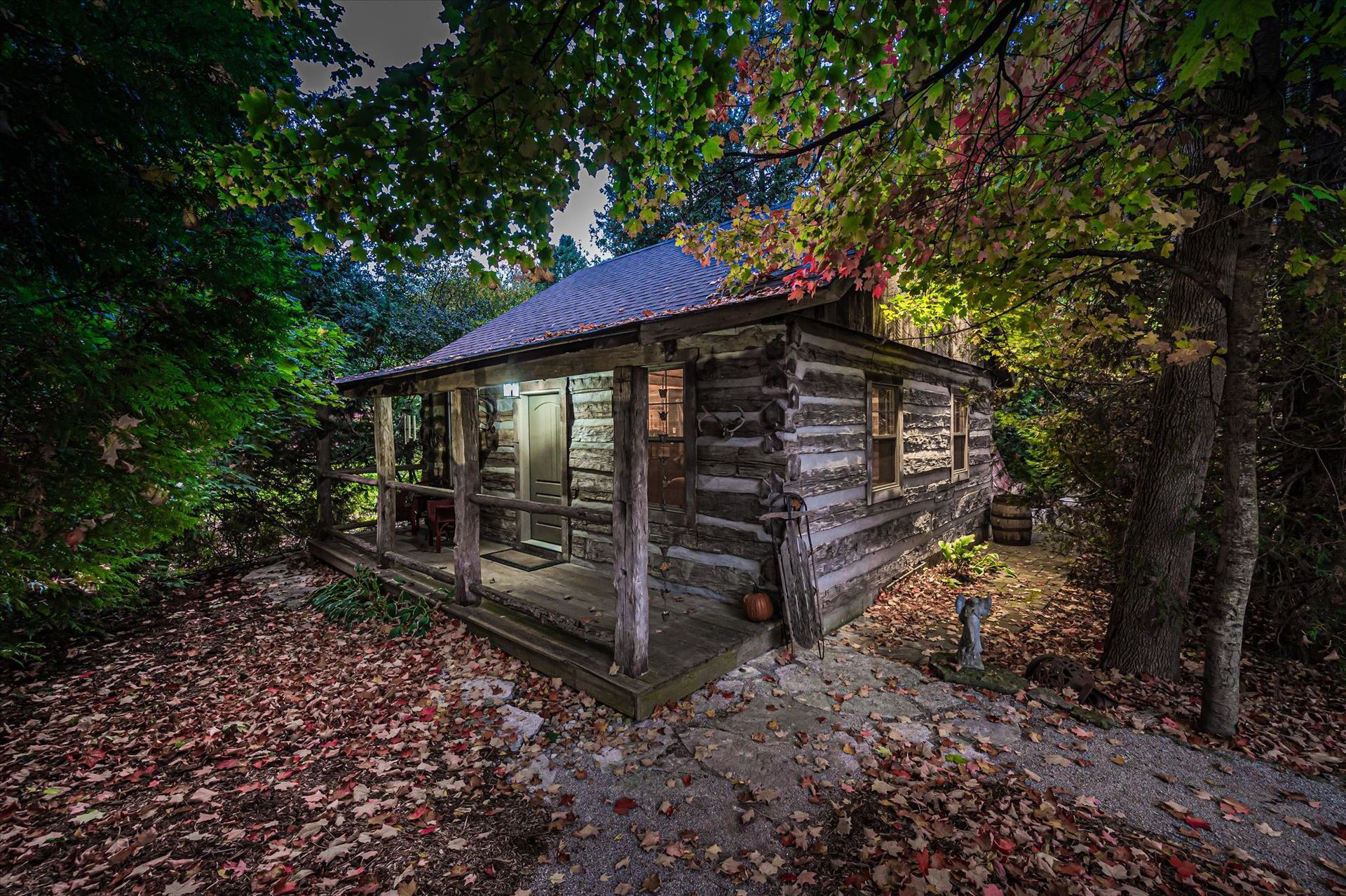 Heritage log cabin at twilight with autumn leaves