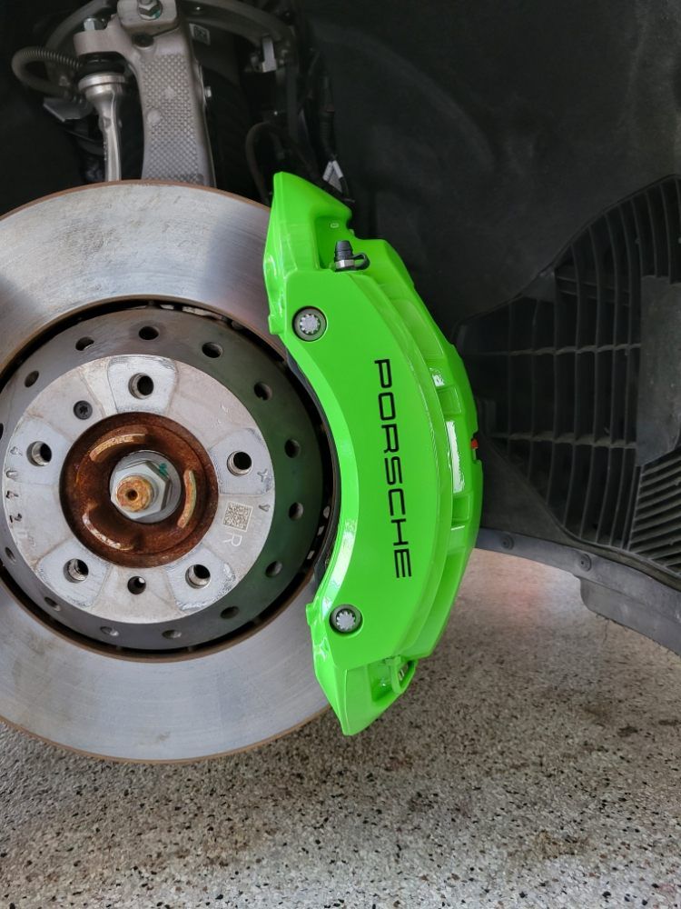 A close up of a green porsche brake caliper on a car.