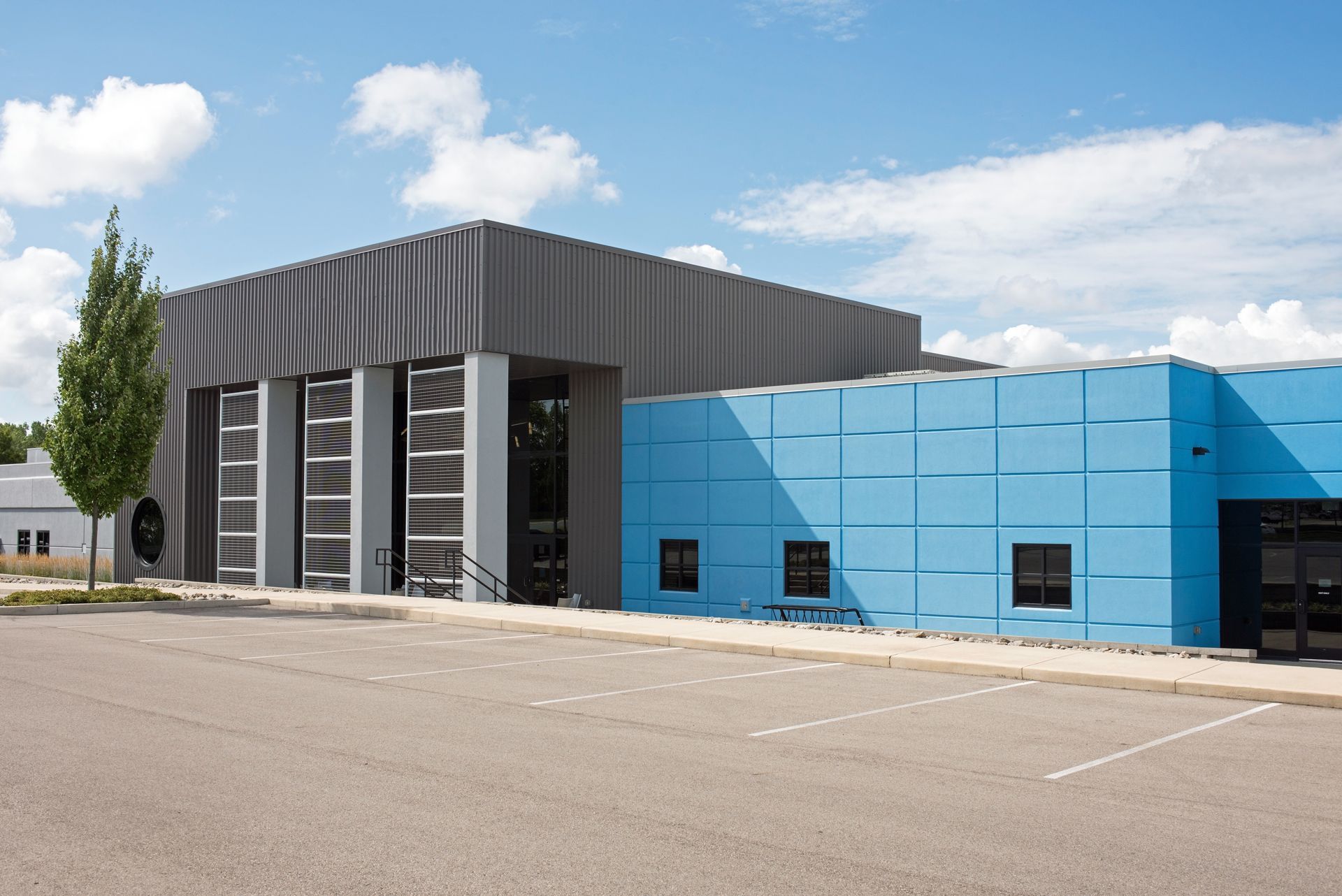 A blue and gray building with a parking lot in front of it