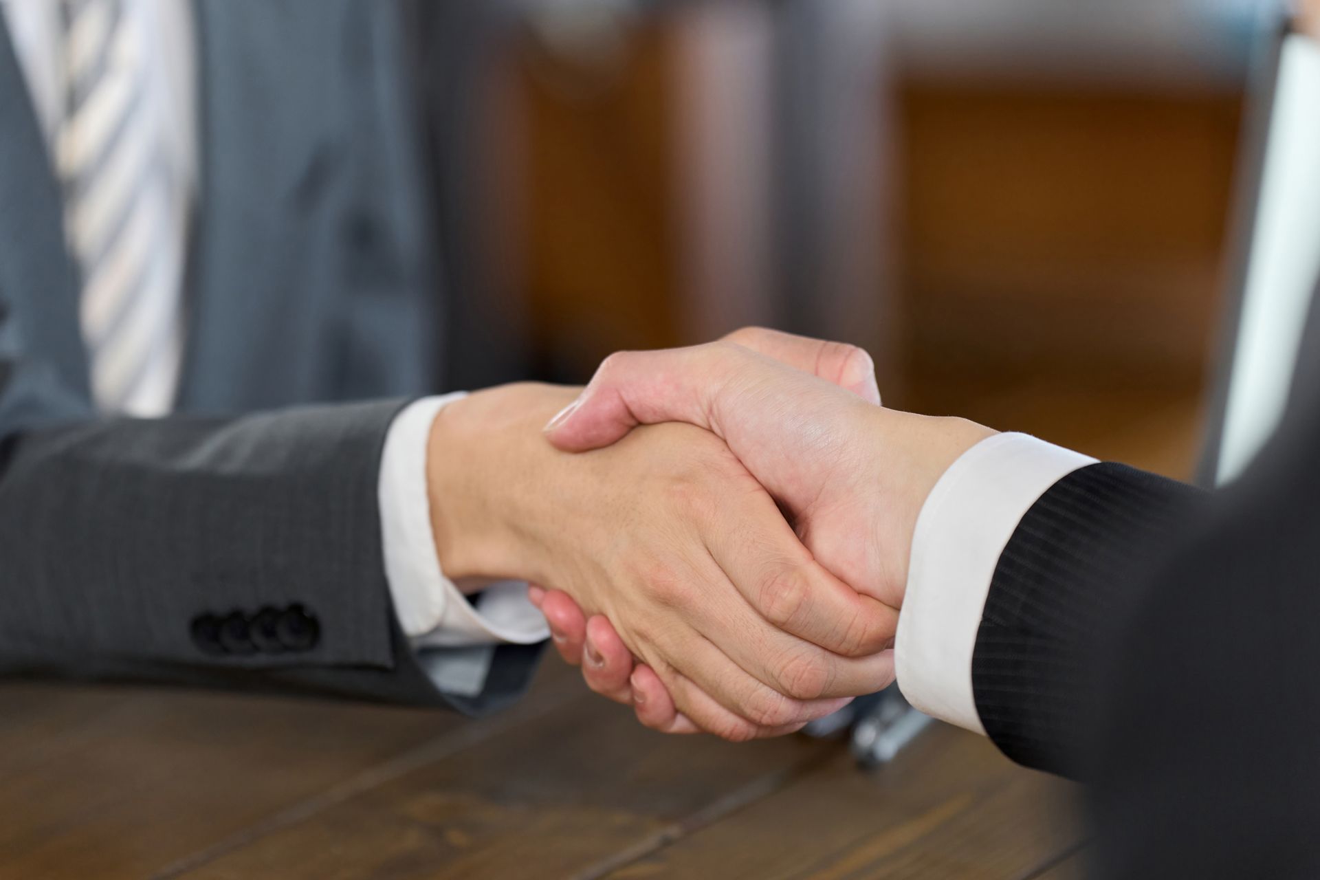 A man and a woman are shaking hands at a table.