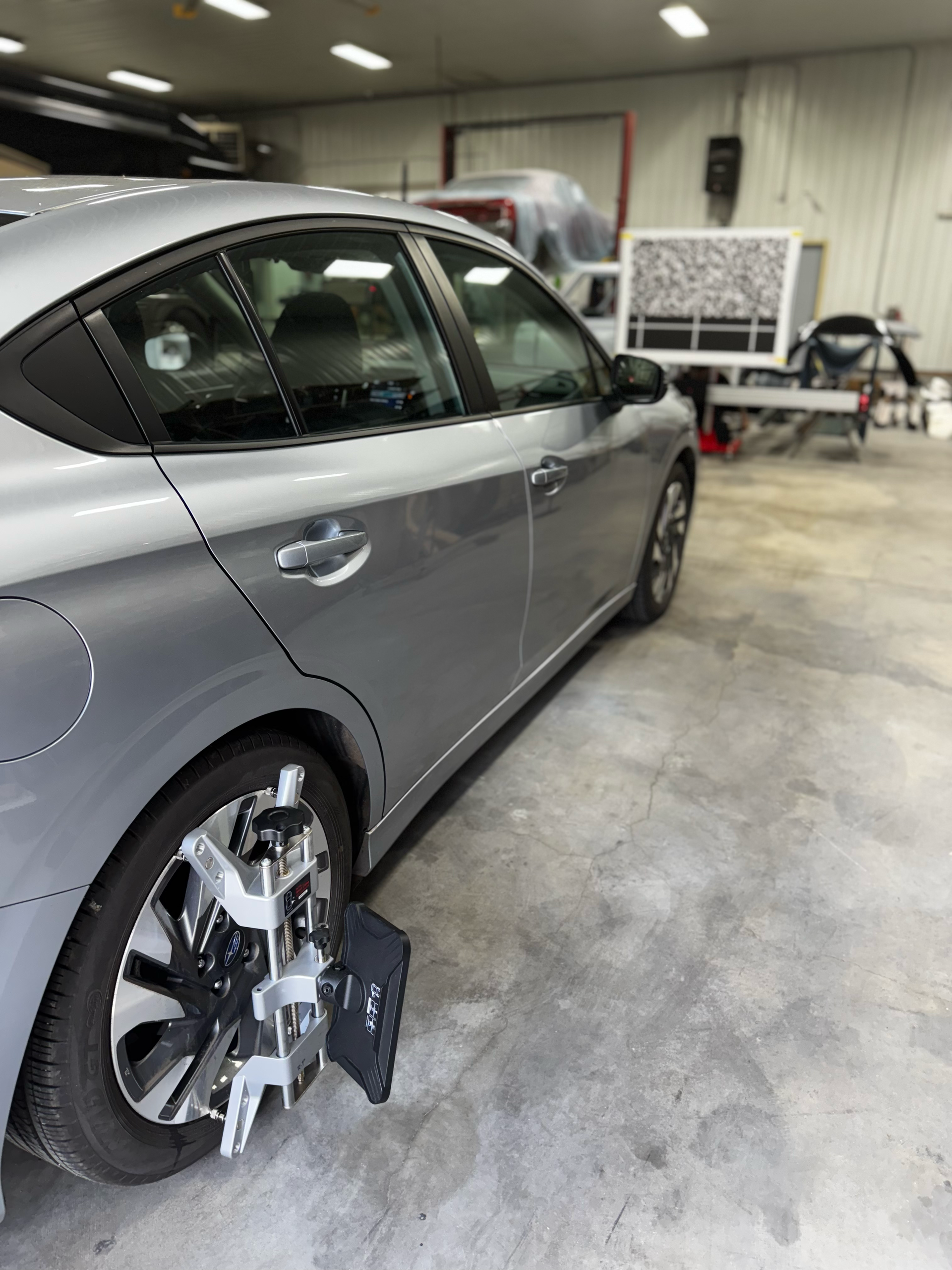A car is sitting in a garage with a wheel alignment target for ADAS calibrations on it