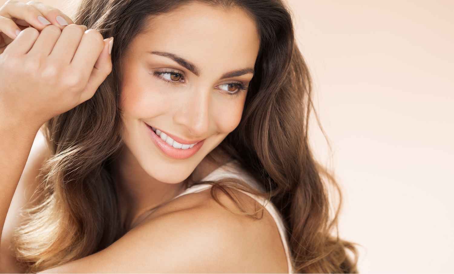 A Woman with Long Hair Is Smiling and Touching Her Hair.