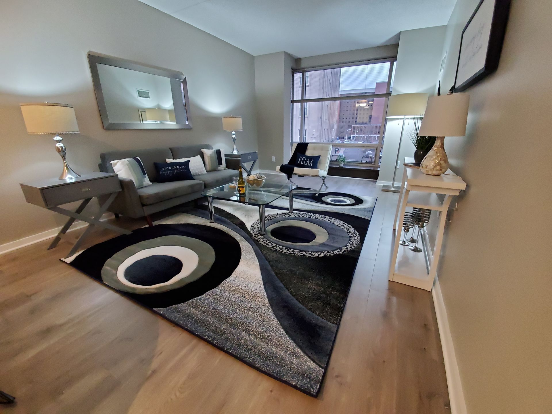 A living room with a couch , chairs , lamps and a rug.