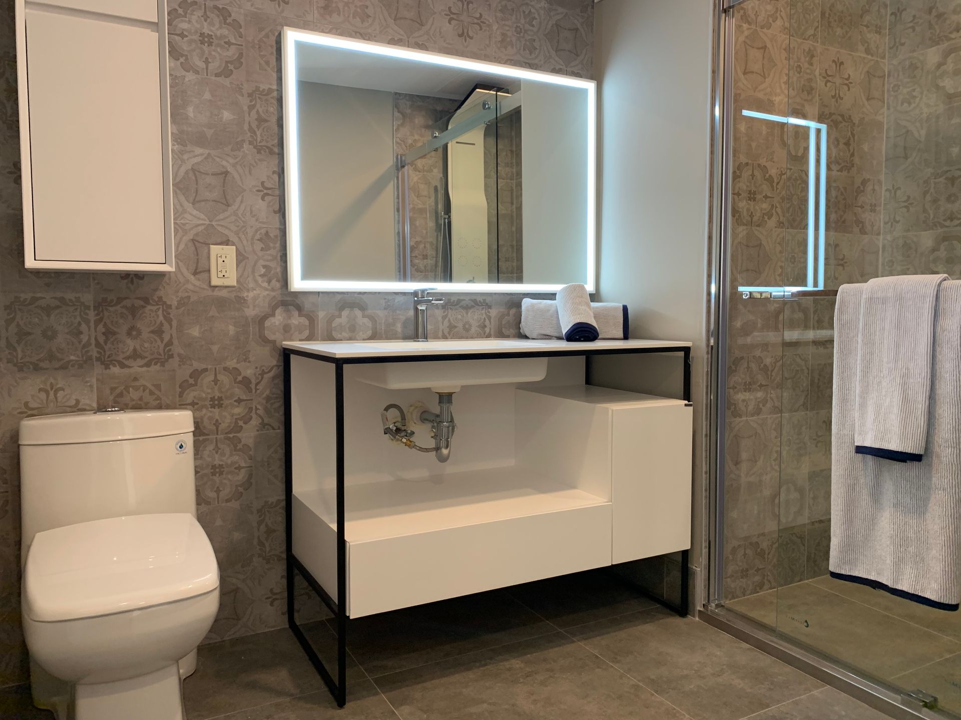 A bathroom with a toilet , sink , mirror and shower.