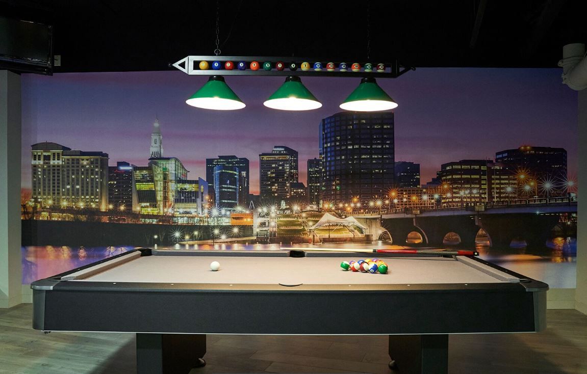 A pool table with a city skyline on the wall behind it