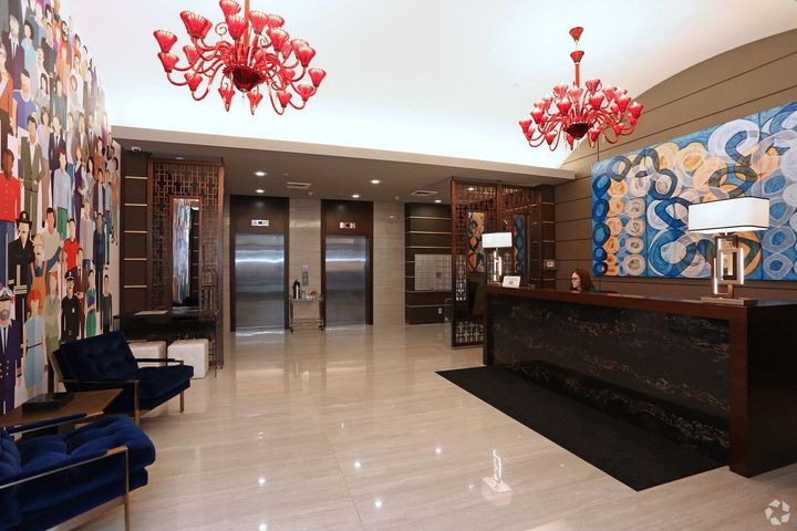 A lobby of a hotel with a red chandelier hanging from the ceiling.