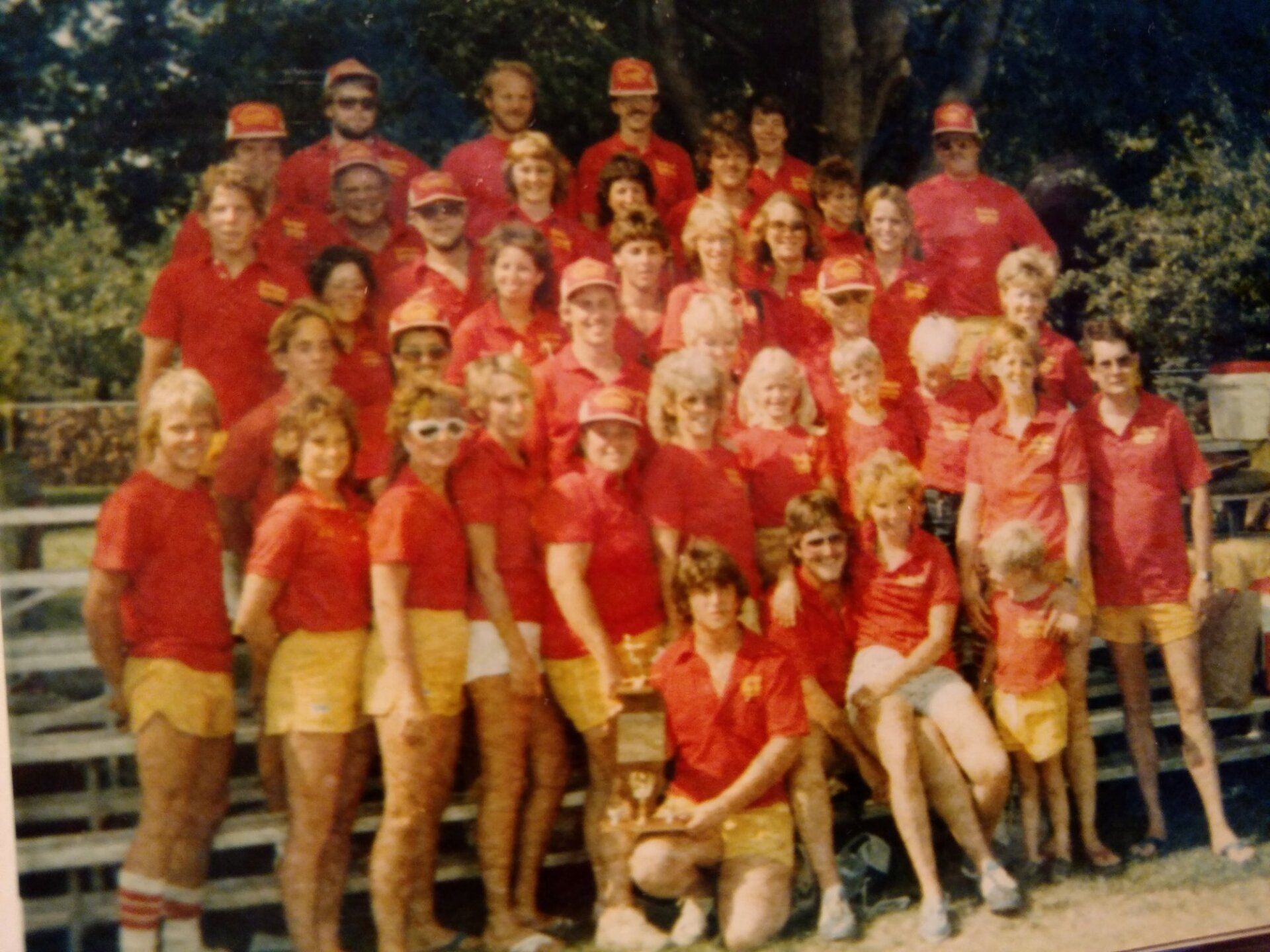 A group of people wearing red shirts and yellow shorts pose for a picture