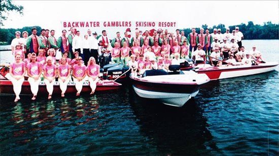A group of people are posing for a picture in front of a sign that says Backwater Gamblers Skisino Resort