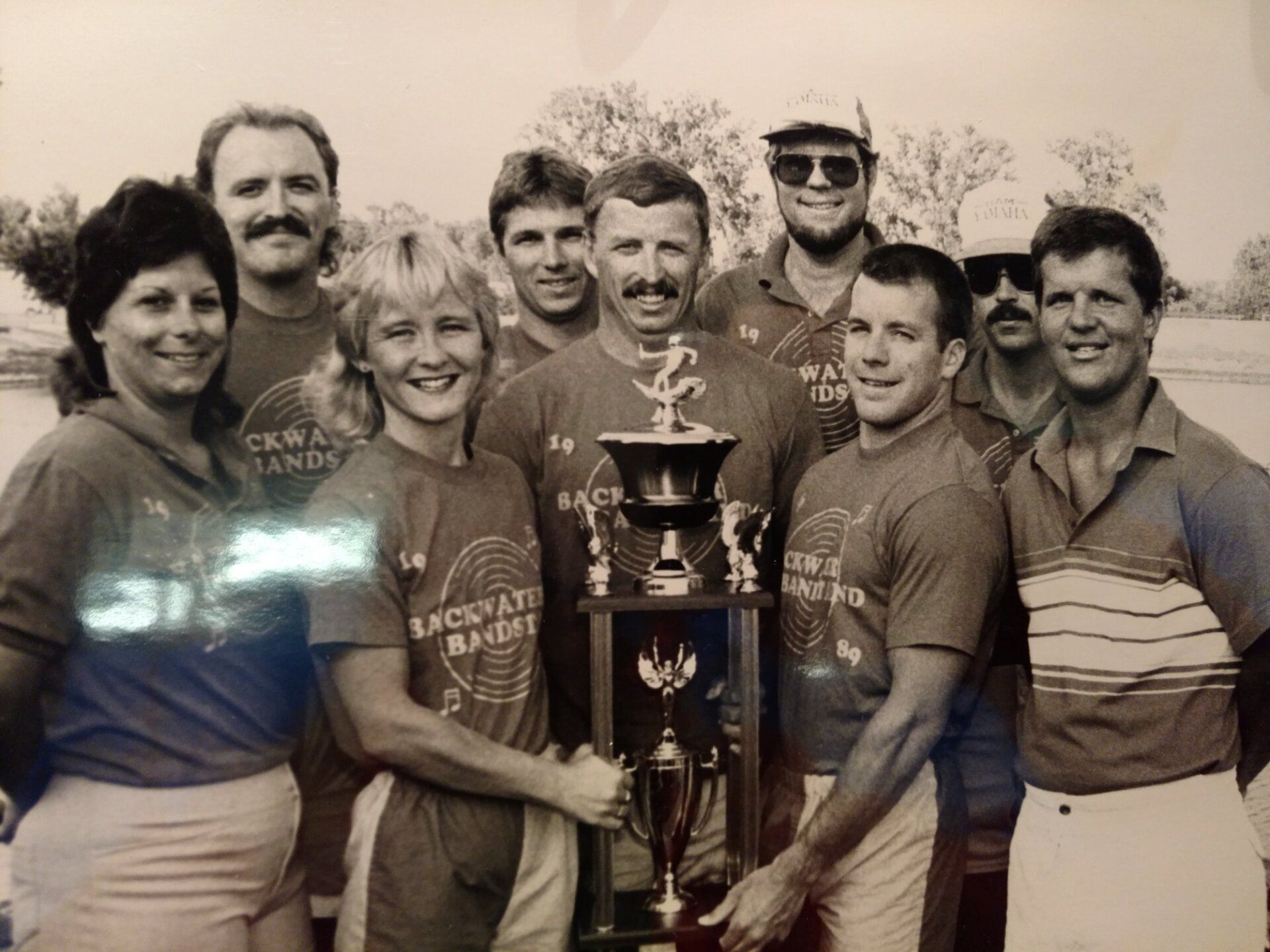 A black and white photo of a group of people holding a trophy
