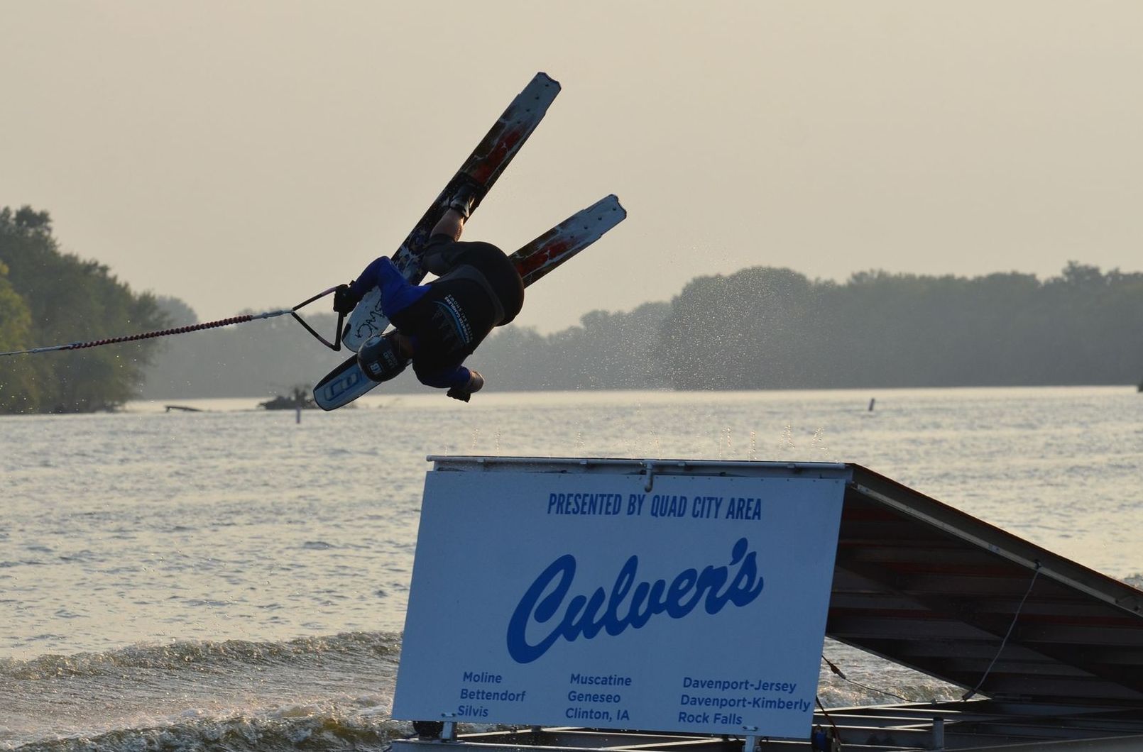 A person is doing a trick in jump off a mini ramp with a Culver 's sign