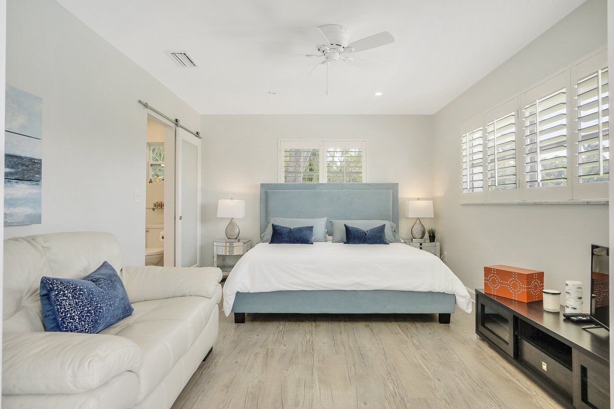 A bedroom with a king size bed , a couch , and a ceiling fan.