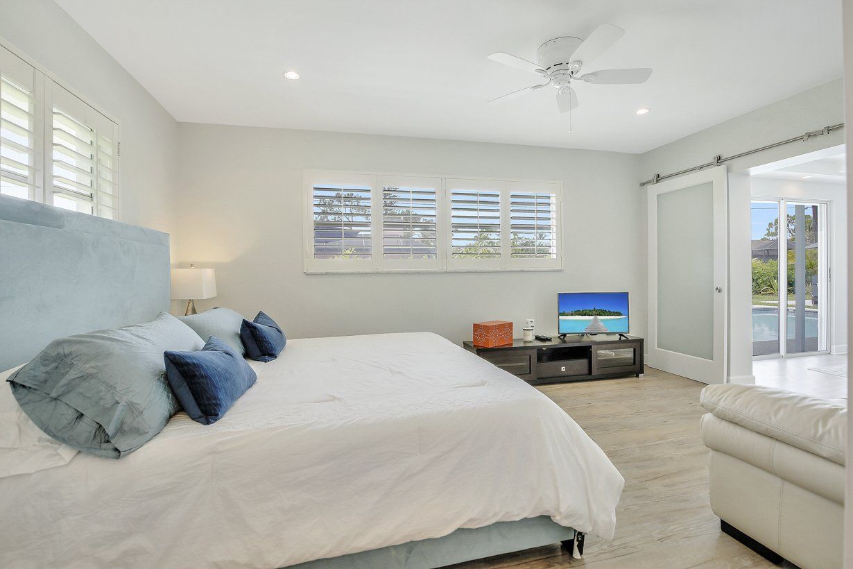 A bedroom with a king size bed , a television , and a ceiling fan.