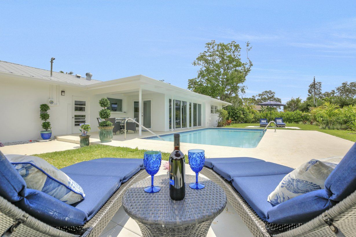 A bottle of wine is sitting on a table in front of a swimming pool.