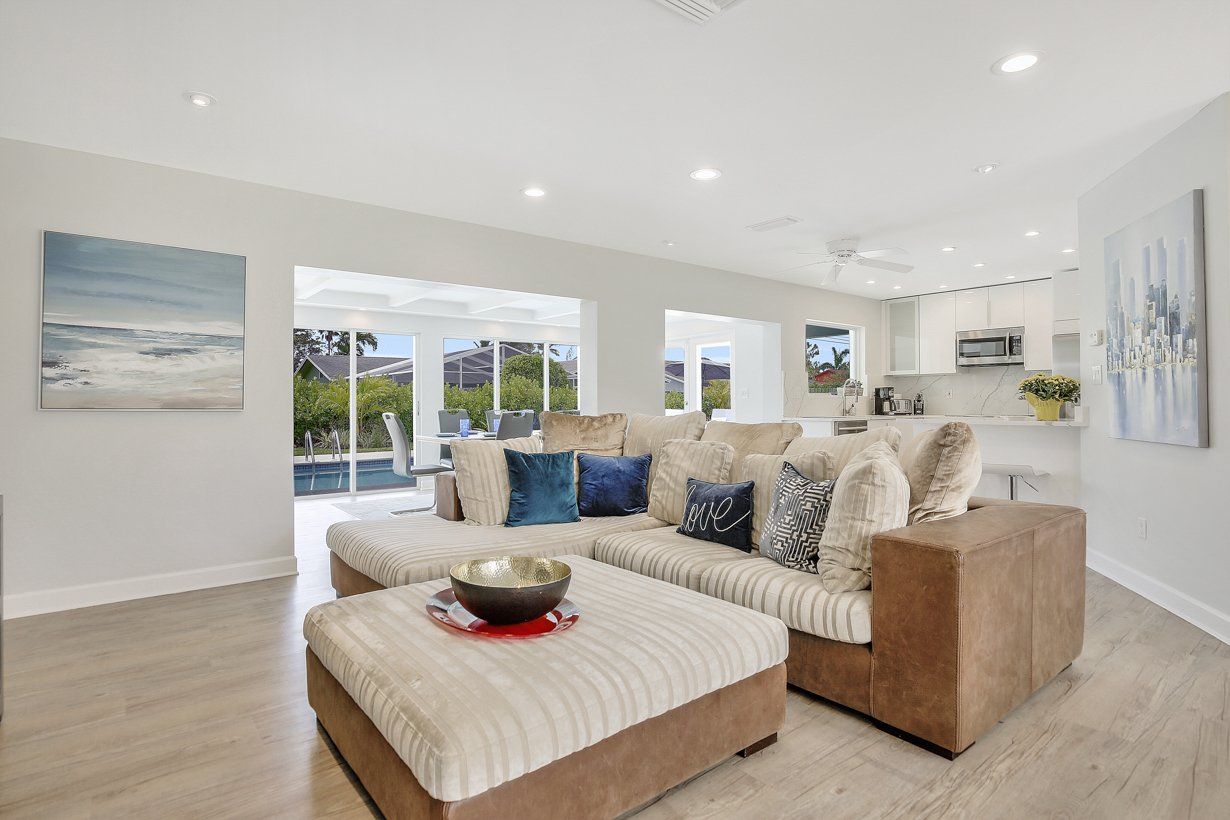 A living room with a couch , ottoman , and paintings on the wall.