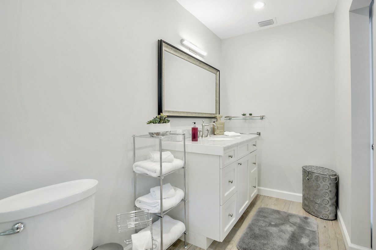A bathroom with a toilet , sink , mirror and towel rack.