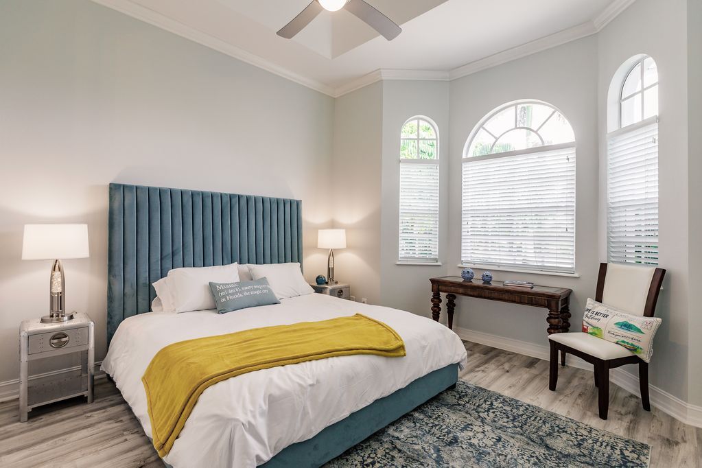 A bedroom with a bed , chair , desk and ceiling fan.