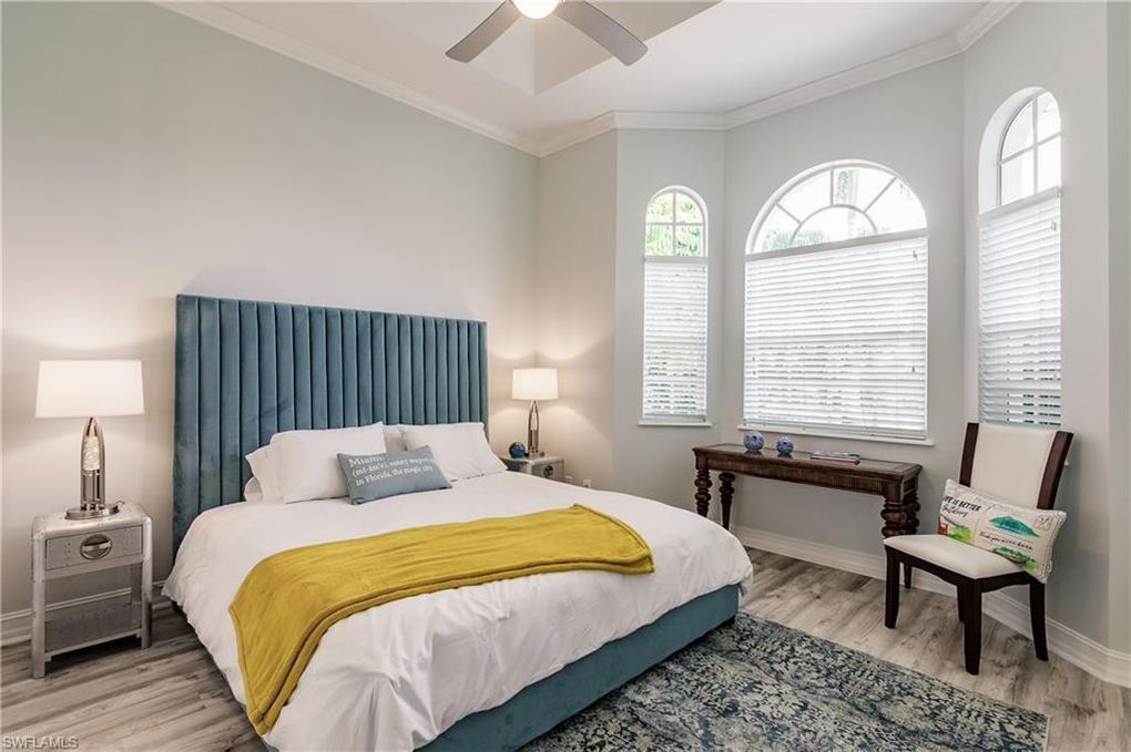 A bedroom with a bed , chair , desk and ceiling fan.