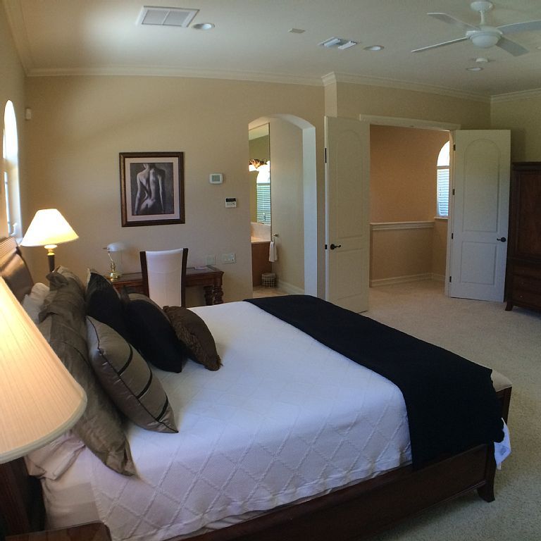A bedroom with a large bed and a ceiling fan