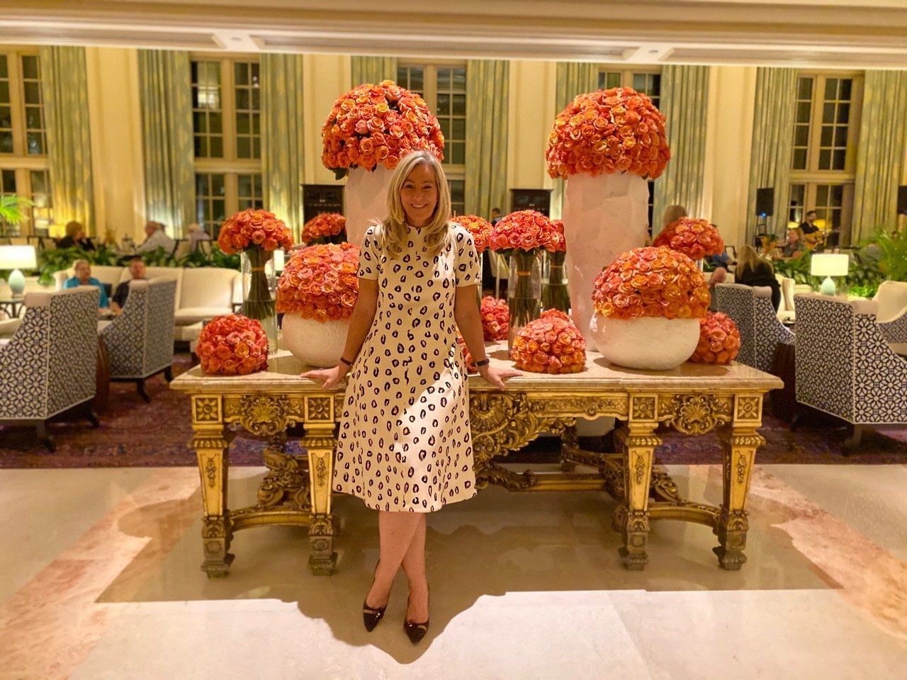 A woman in a dress is standing in front of a table with flowers on it.