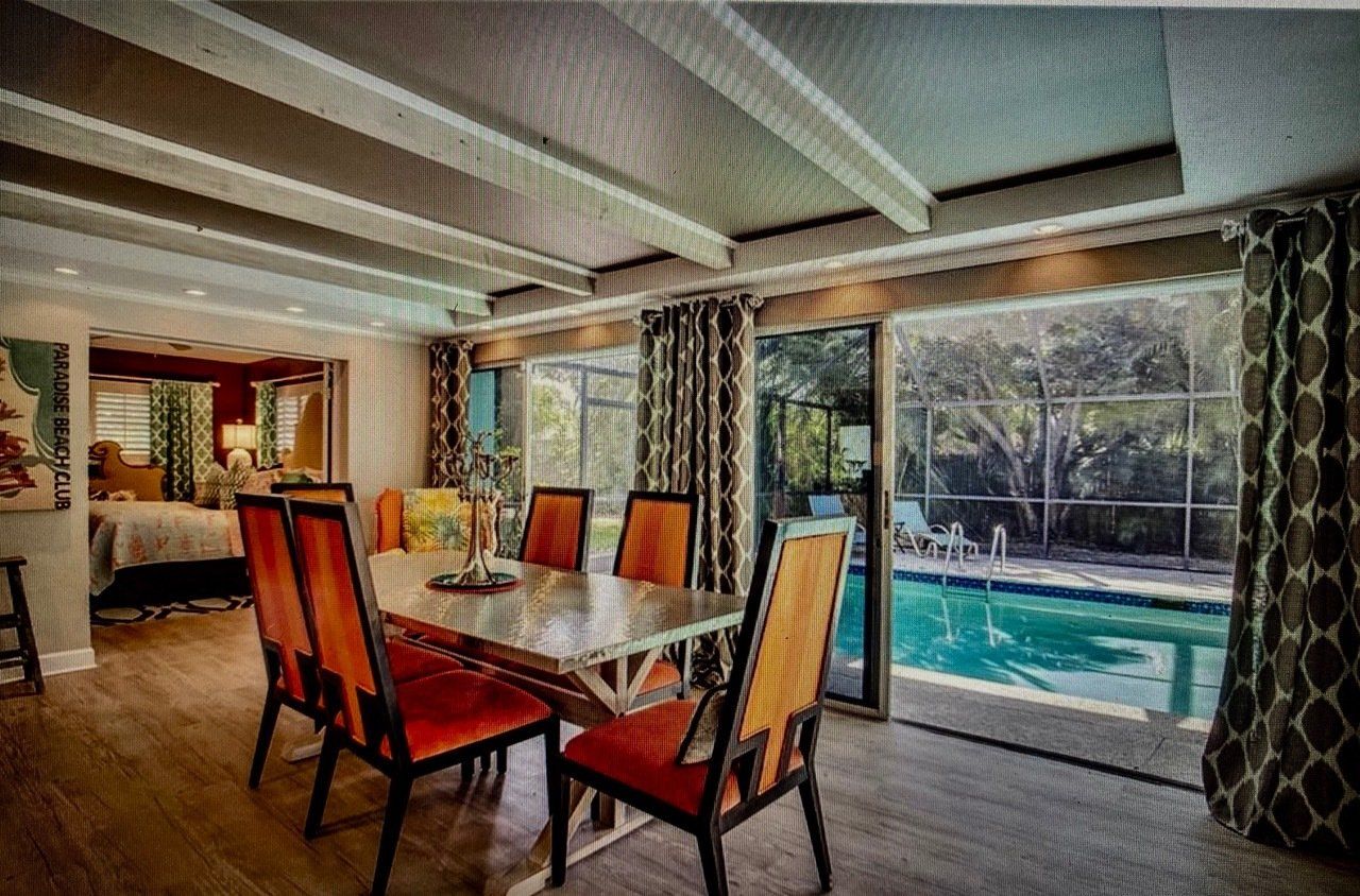A dining room with a table and chairs and a pool in the background.